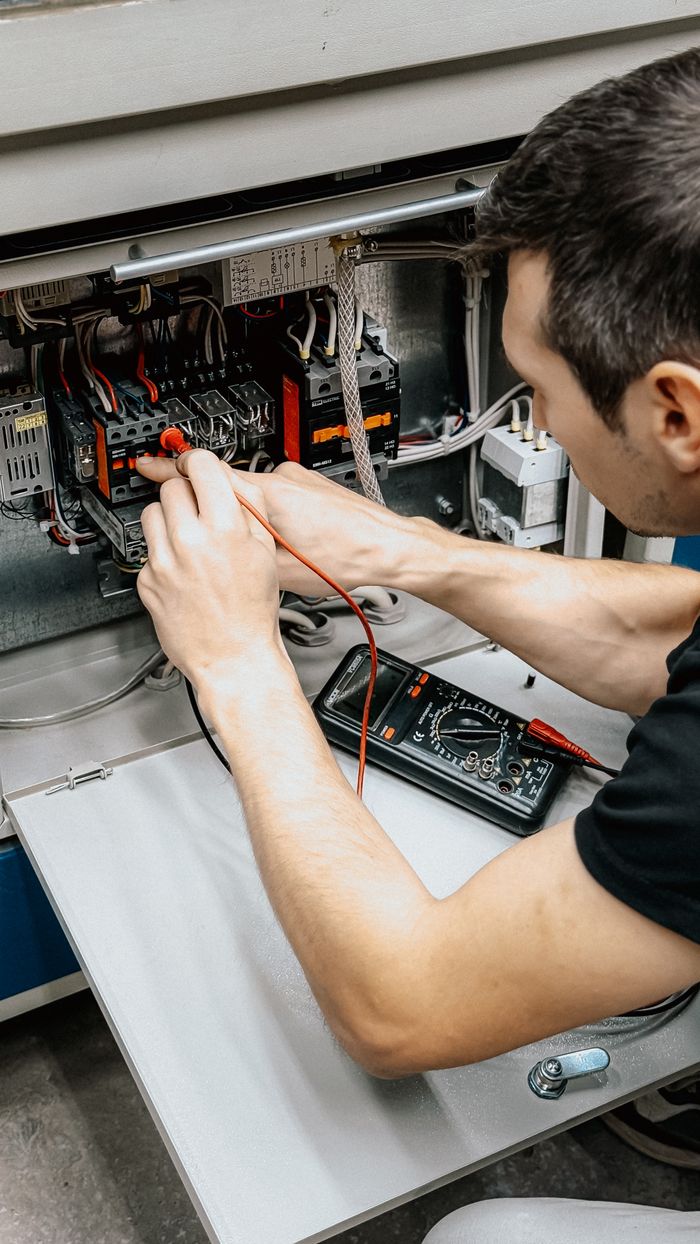 services-01 An electrician uses a multimeter to test and diagnose connections in an open electrical panel.